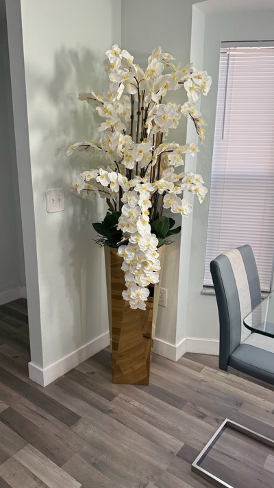 Kaskadierende weiße Orchideen in einer goldgeschliffenen Vase