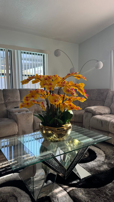 Kaskadierende gelbe Orchideen in einer goldfarbenen Edelstahlvase